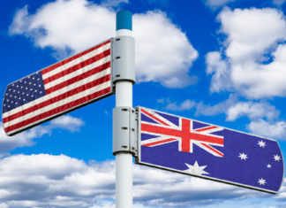 Austrália ou Estados Unidos: qual é o melhor destino para imigrar? Placa apontando para direções diferentes com as bandeiras dos Estados Unidos e da Austrália em cada placa.