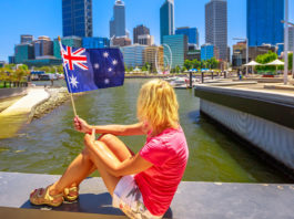 Mulher segurando bandeira da australia em frente a cidade de perth