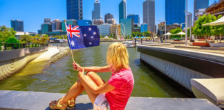 Mulher segurando bandeira da australia em frente a cidade de perth