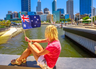 Mulher segurando bandeira da australia em frente a cidade de perth