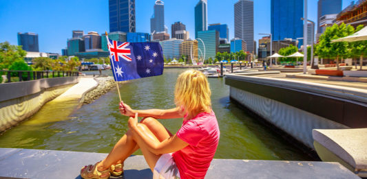 Mulher segurando bandeira da australia em frente a cidade de perth