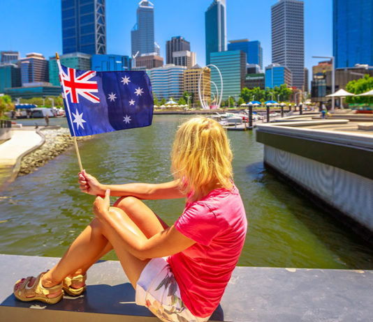 Mulher segurando bandeira da australia em frente a cidade de perth